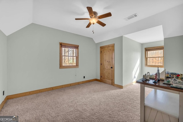 interior space featuring multiple windows, vaulted ceiling, light colored carpet, and ceiling fan