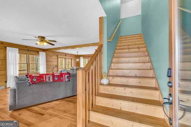 stairway with hardwood / wood-style flooring, ceiling fan, and wood walls