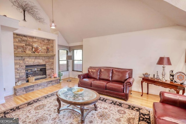 living room featuring lofted ceiling, hardwood / wood-style floors, and a stone fireplace