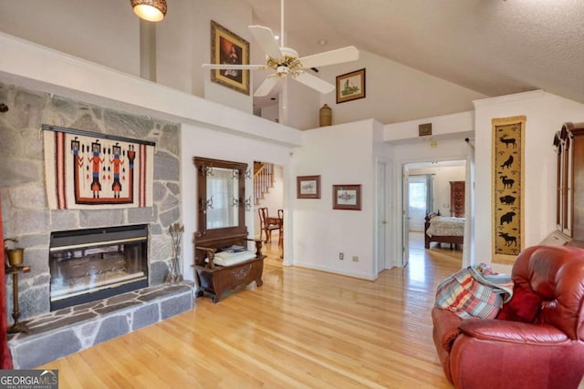 living room with wood-type flooring, lofted ceiling, ceiling fan, and a fireplace