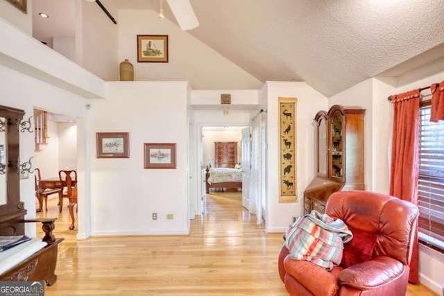 sitting room featuring vaulted ceiling, light hardwood / wood-style floors, and a textured ceiling