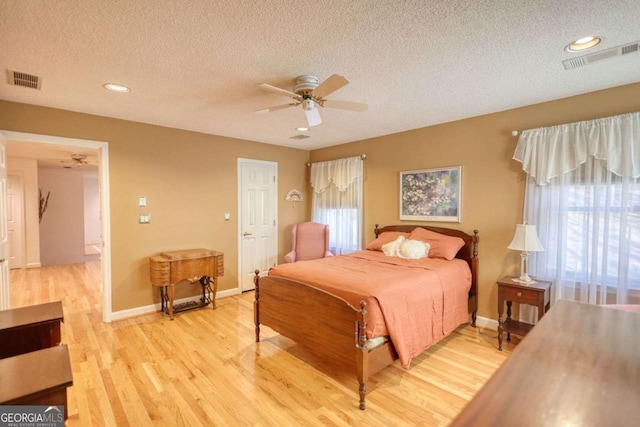 bedroom featuring ceiling fan, light hardwood / wood-style flooring, and a textured ceiling