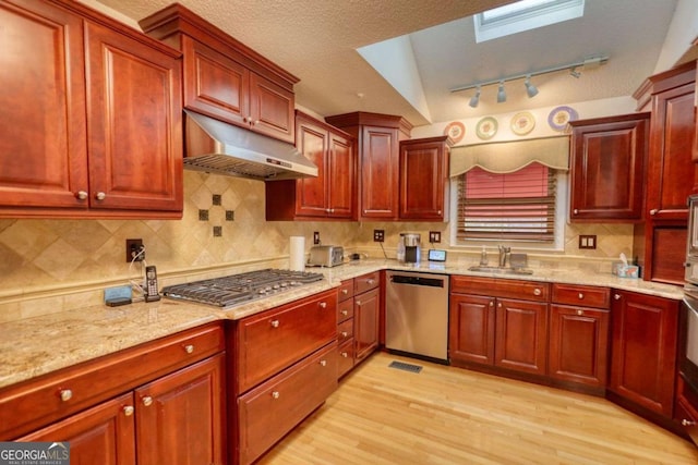 kitchen featuring sink, light hardwood / wood-style flooring, appliances with stainless steel finishes, backsplash, and a textured ceiling