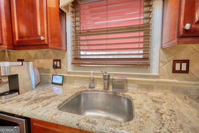 kitchen featuring light stone counters, sink, and backsplash