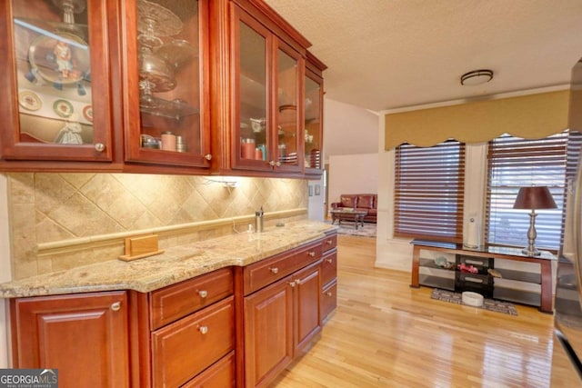 kitchen with light stone counters, a textured ceiling, light hardwood / wood-style flooring, and tasteful backsplash