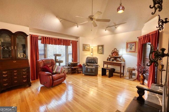 living room with ceiling fan, track lighting, a textured ceiling, and light hardwood / wood-style floors