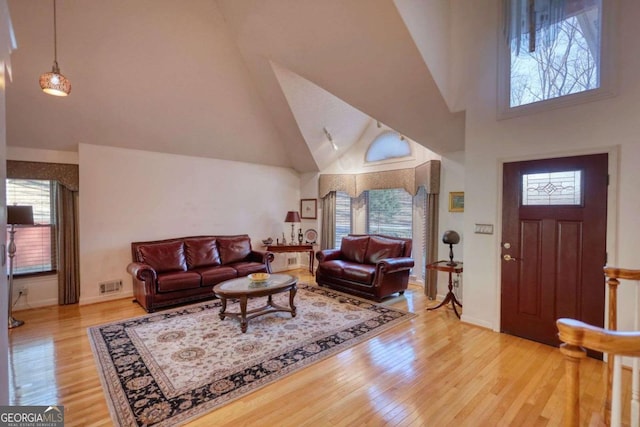 living room featuring high vaulted ceiling, a healthy amount of sunlight, and light hardwood / wood-style floors