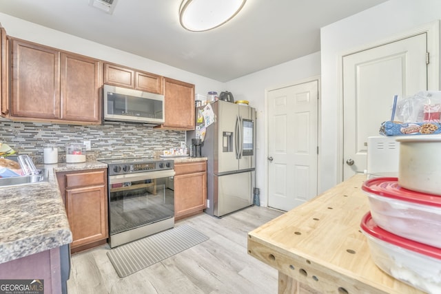 kitchen featuring backsplash, light hardwood / wood-style flooring, sink, and appliances with stainless steel finishes