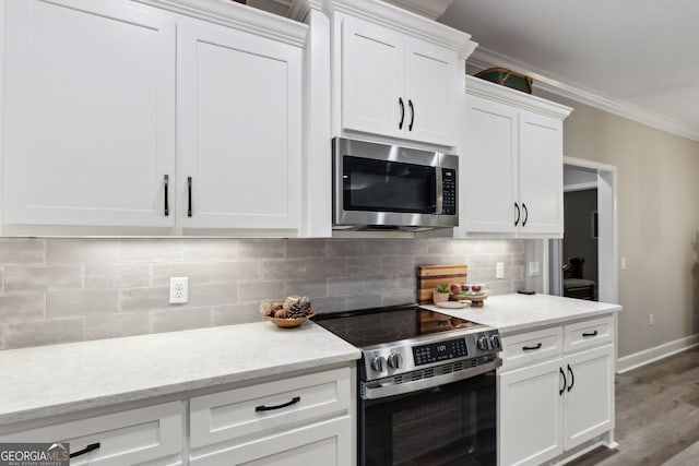 kitchen with white cabinetry, tasteful backsplash, ornamental molding, appliances with stainless steel finishes, and light stone countertops