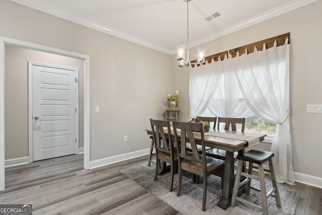 dining area with hardwood / wood-style floors, crown molding, and a chandelier