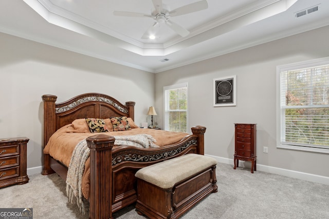 bedroom with ceiling fan, light colored carpet, ornamental molding, and a raised ceiling