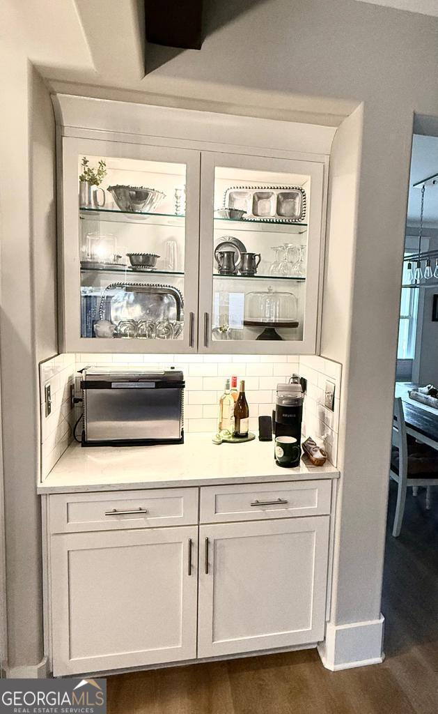 bar featuring white cabinetry, dark wood-type flooring, and tasteful backsplash