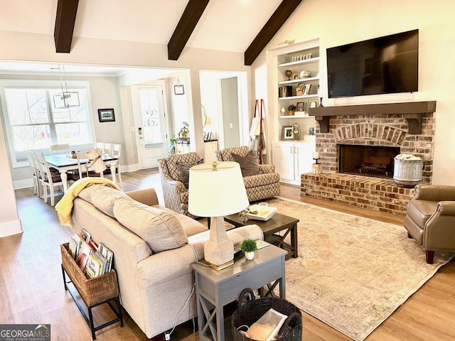 living room featuring wood-type flooring, vaulted ceiling with beams, built in features, and a fireplace