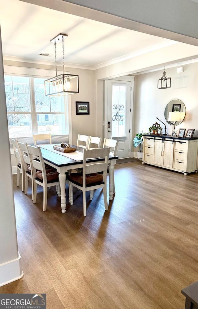 dining area with crown molding and wood-type flooring