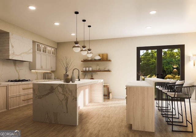 kitchen featuring decorative backsplash, dark hardwood / wood-style flooring, a kitchen island with sink, and a breakfast bar area