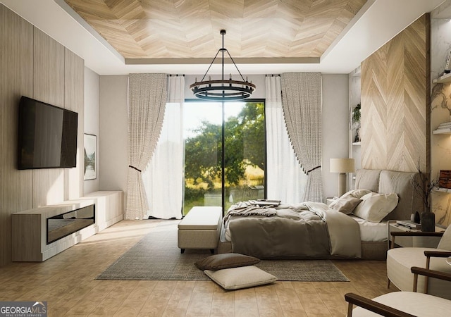 bedroom with a chandelier, light wood-type flooring, and a tray ceiling