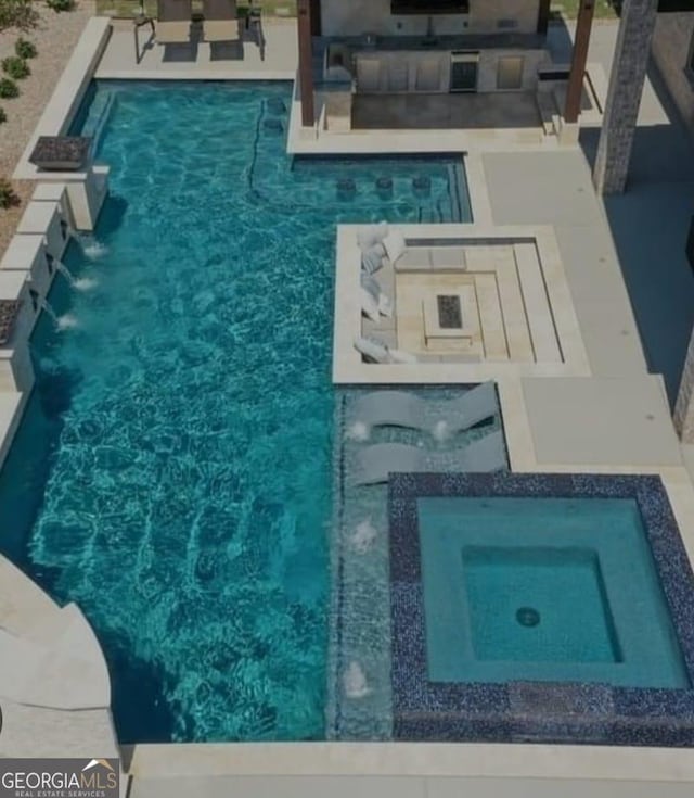 view of swimming pool featuring an in ground hot tub, pool water feature, and a patio area