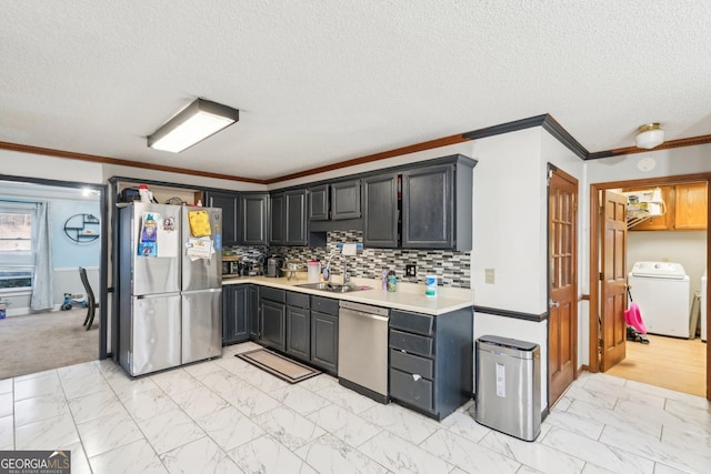 kitchen with sink, crown molding, backsplash, stainless steel appliances, and washer / dryer