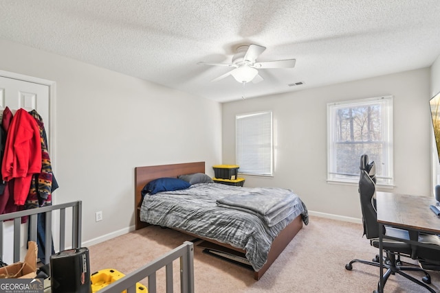 carpeted bedroom featuring ceiling fan and a textured ceiling