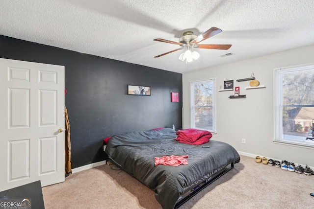 bedroom with ceiling fan, light colored carpet, and a textured ceiling