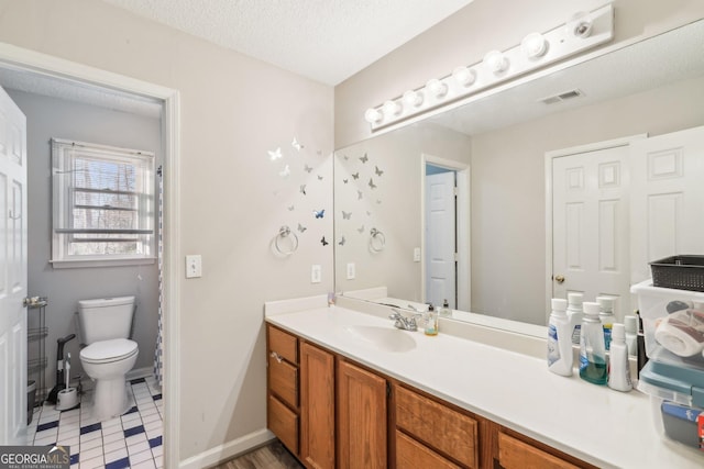 bathroom featuring vanity, toilet, and a textured ceiling