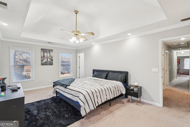 bedroom with crown molding, light colored carpet, ceiling fan, and a tray ceiling