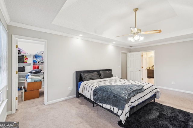 carpeted bedroom featuring crown molding, ceiling fan, a tray ceiling, a walk in closet, and a closet