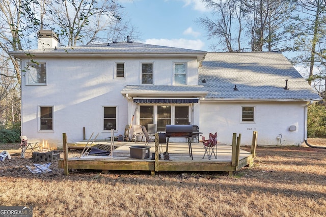 rear view of house with a wooden deck and a fire pit