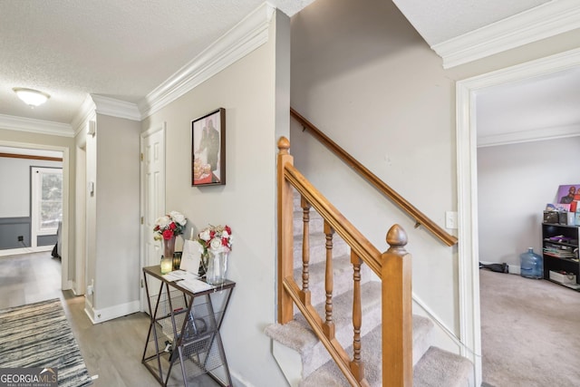 stairway with ornamental molding, wood-type flooring, and a textured ceiling