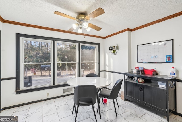 dining area featuring ornamental molding, ceiling fan, and a textured ceiling