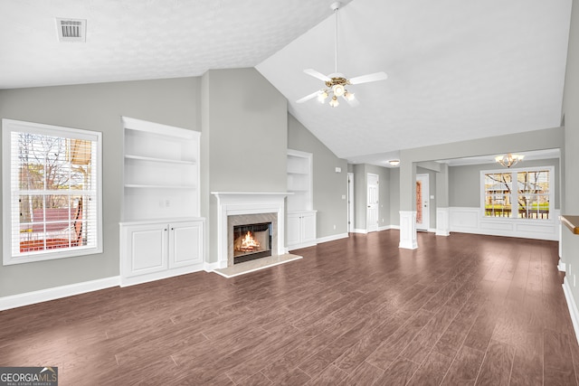 unfurnished living room featuring a fireplace, dark wood-type flooring, plenty of natural light, and built in features