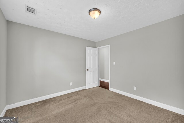 empty room featuring a textured ceiling and carpet