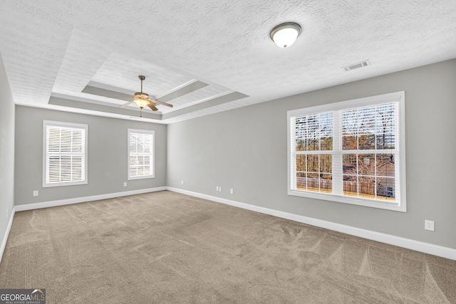 spare room with ceiling fan, a raised ceiling, a textured ceiling, and carpet