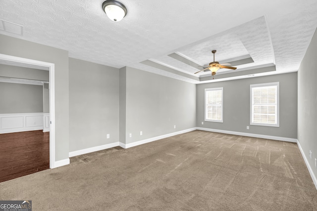 unfurnished bedroom featuring a raised ceiling, carpet floors, and a textured ceiling