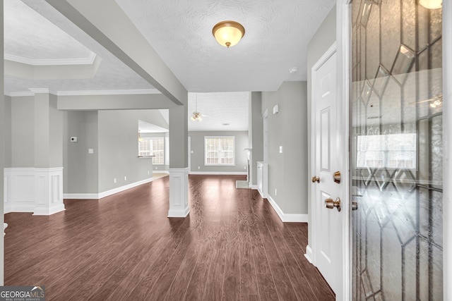 foyer entrance featuring a textured ceiling, ornamental molding, dark hardwood / wood-style floors, ceiling fan, and decorative columns