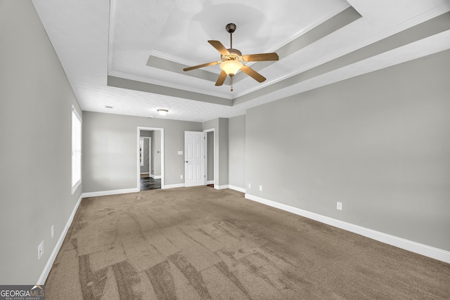 empty room with carpet, ceiling fan, a raised ceiling, crown molding, and a textured ceiling