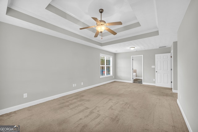 carpeted empty room with a raised ceiling, crown molding, and ceiling fan