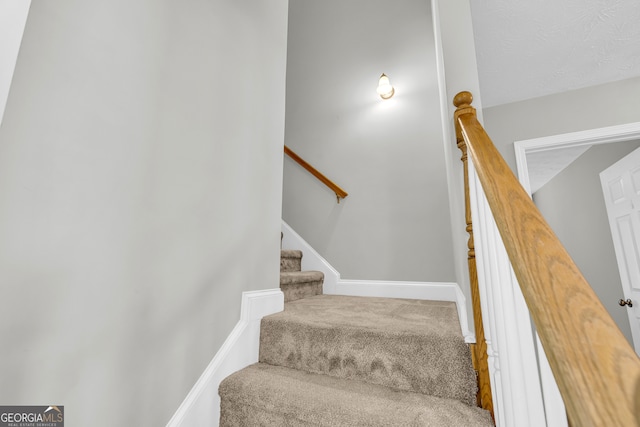 stairway with carpet flooring and a textured ceiling