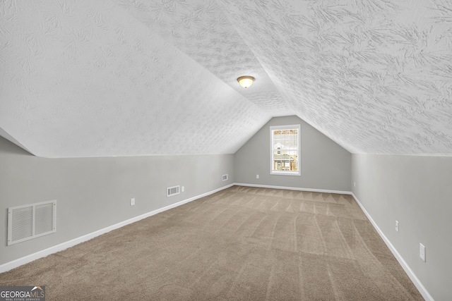 bonus room featuring lofted ceiling, carpet flooring, and a textured ceiling