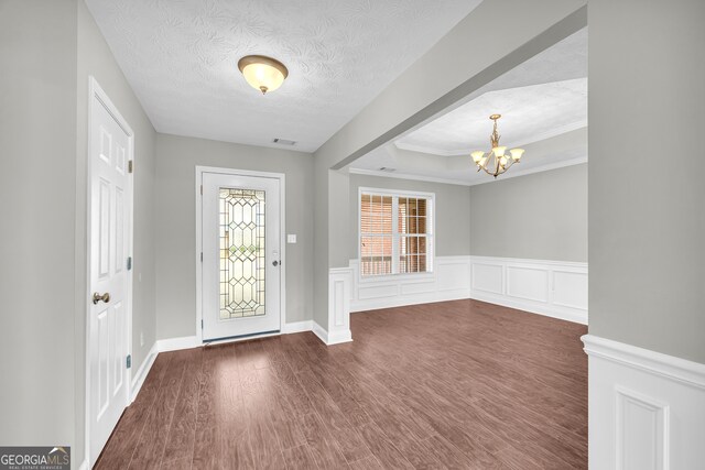 entrance foyer featuring an inviting chandelier, a healthy amount of sunlight, dark wood-type flooring, and a textured ceiling