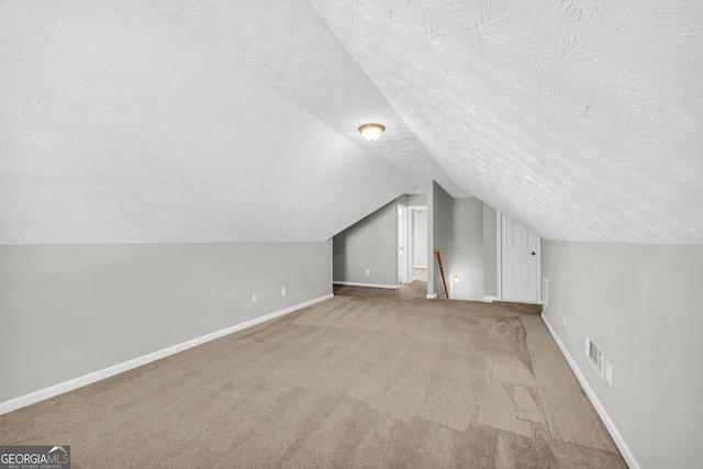 additional living space with lofted ceiling, carpet flooring, and a textured ceiling