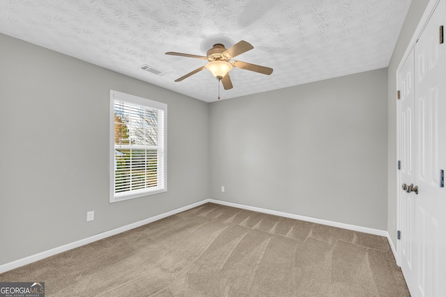 unfurnished room featuring carpet, a textured ceiling, and ceiling fan