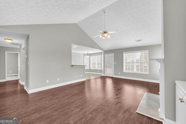 unfurnished living room with ceiling fan, lofted ceiling, dark wood-type flooring, and a textured ceiling