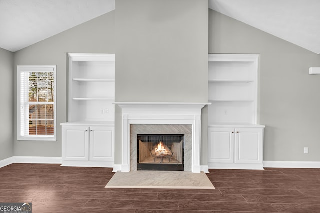 unfurnished living room featuring lofted ceiling, dark hardwood / wood-style flooring, and a premium fireplace