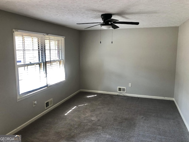 empty room featuring dark colored carpet, ceiling fan, and a textured ceiling