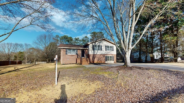 tri-level home with brick siding and a front yard