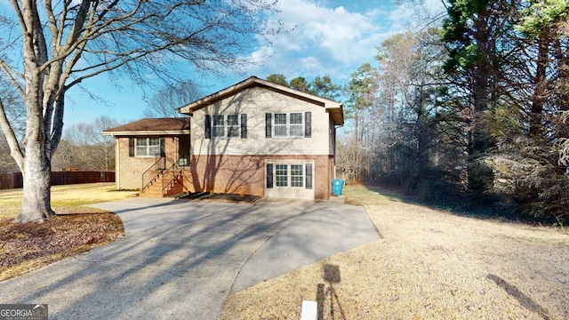 split level home featuring brick siding, fence, and driveway