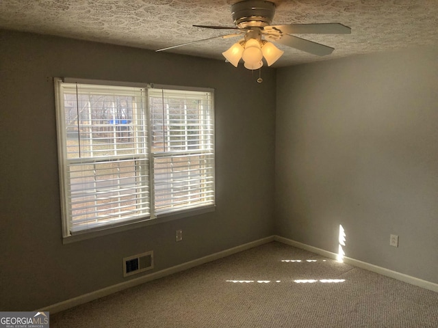 carpeted empty room featuring ceiling fan and a textured ceiling