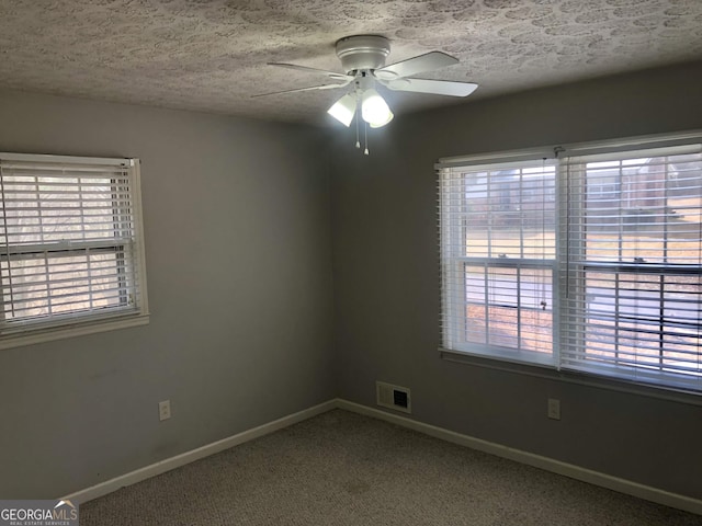 carpeted spare room with ceiling fan and a textured ceiling