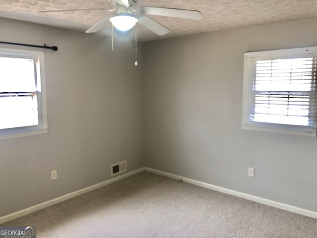 carpeted spare room featuring ceiling fan and a textured ceiling